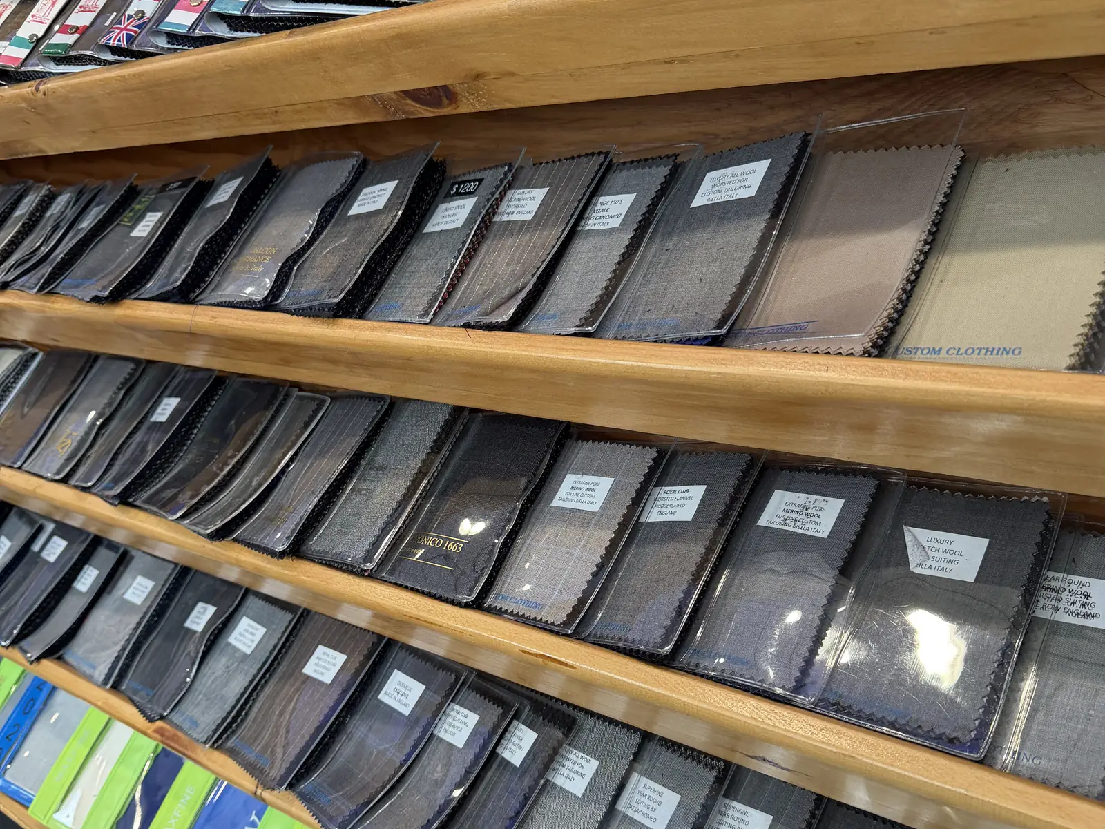 Suiting fabric books lined up on the shop wall at Komal's Suits